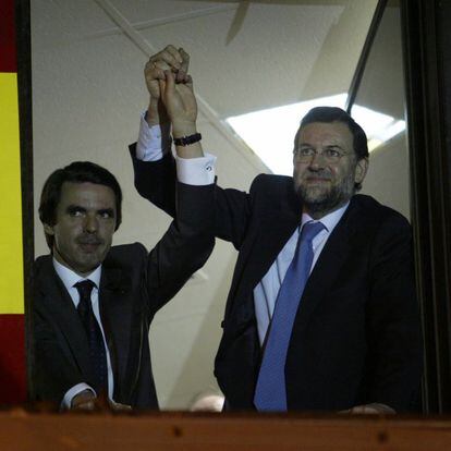 José María Aznar (izquierda) y Mariano Rajoy (derecha) saludan a los simpatizantes del PP desde la ventana de la sede del PP de Madrid, tras los resultados de las elecciones generales del 14-M del 2000.