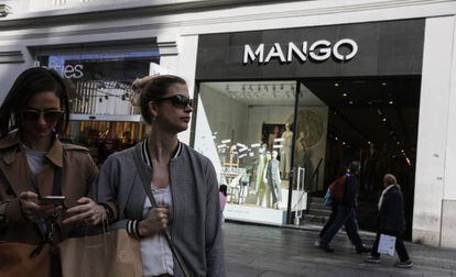 Dos clientas usan el móvil frente a una tienda mango en Madrid.