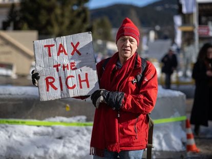 Un activista británico con un cartel que reza "que paguen impuestos los ricos", el pasado enero en Davos, Suiza, durante el Foro Económico Mundial.