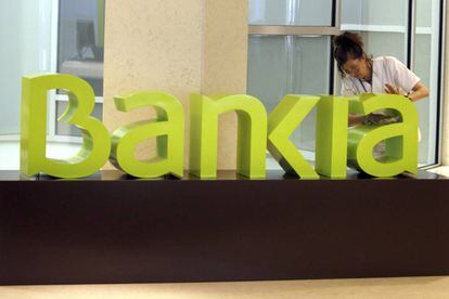 Una operaria limpia el logo de Bankia 