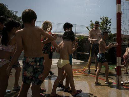 Alumnos de la escuela primaria Fort Pienc, de Barcelona, juegan con agua en el patio del centro para refrescarse