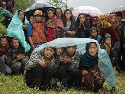 Habitants de Gumda esperen sota la pluja l'arribada d'un helicòpter.
