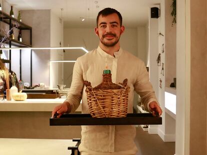 Carlos Casillas, con una damajuana, garrafa para servir vino. 