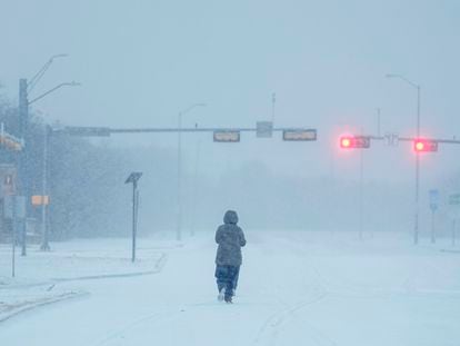 Un hombre camina sobre una avenida cubierta de nieve, en la ciudad texana de Grand Pairie (EE UU), este lunes.