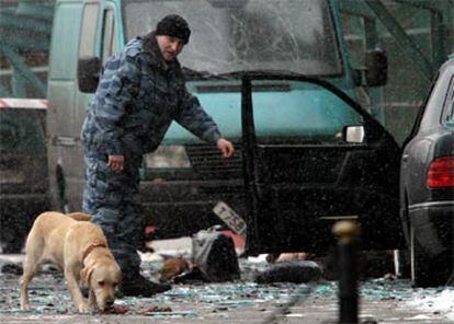 Un policía ayudado por un perro inspecciona las inmediaciones del Hotel Nacional en Moscú tras la explosión que ha causado al menso cinco muertos.