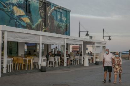 Una pareja pasa por delante de un restaurante en el puerto de Corralejo, en Fuerteventura, el 3 de octubre.