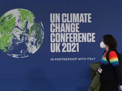 Una mujer pasa frente a un cartel que anuncia la cumbre del clima que se celebra en Glasgow.