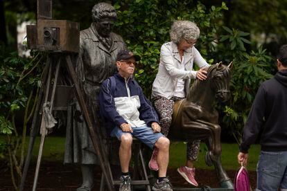 Unos turistas se hacen fotos sentados en la estatua de La Torera, este martes en Oviedo.
