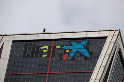 Sustitución del logo de Bankia por el de CaixaBank en una de las torres KIO, en Madrid.