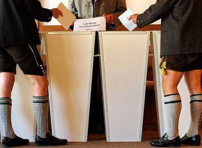 Dos hombres vestidos de forma tradicional bávara depositan su voto en las elecciones generales en un colegio de Bayrischzell.