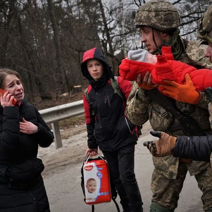 Vlod holds Emma while her mother, Julia, tries to locate her husband on the run in Irpin, Ukraine.