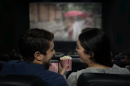 Una pareja consume palomitas en una sala de cine.