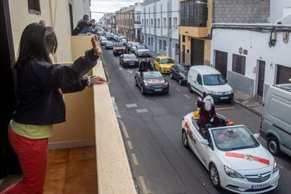 Una niña saluda desde un balcón a los Reyes Magos que desfilaron en descapotable y con mascarilla por los barrios de Arrecife de Lanzarote.