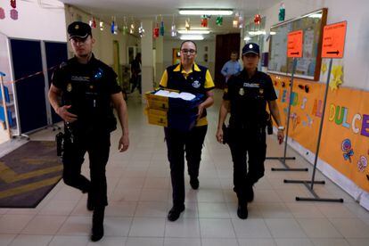 Agentes de la Policía Nacional escoltan a una cartera en el colegio electoral León Solá de Melilla.