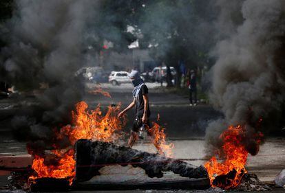 Un manifestante pasa tras una barricada de fuego durante la jornada de hulega en Caracas.