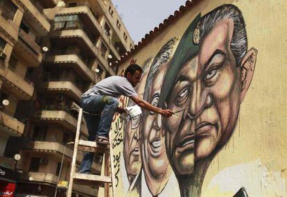 Un hombre pinta un mural en El Cairo combinando los rostros de Mubarak y Tantawi.