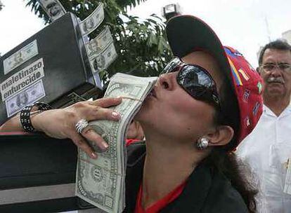 Una manifestante besa un falso fajo de dólares durante una protesta contra la corrupción ayer en Caracas.