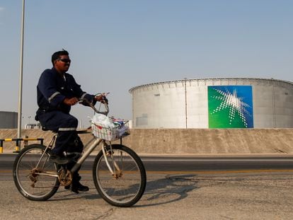Un empleado pasa en bicicleta cerca de un tanque de petróleo de Aramco, la petrolera estatal saudí.