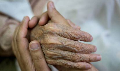 Una persona da la mano a un anciano. 