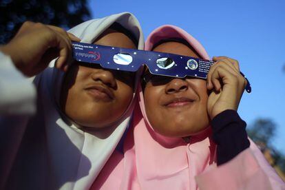 Dues dones comparteixen les mateixes ulleres protectores durant l'eclipsi solar, a Kuala Lumpur (Malàisia).