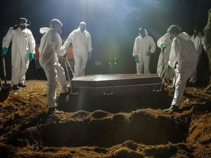 Trabajadores del cementerio de Vila Formosa (São Paulo) entierran un ataud de un fallecido por covid-19.