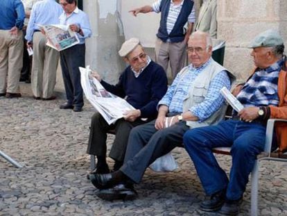 Jubilados portugueses leen la prensa en una calle.