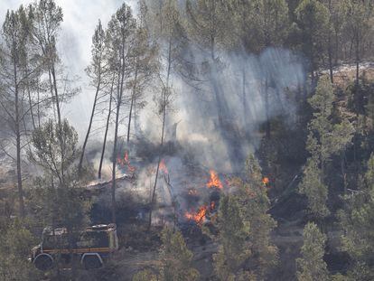 LOS PEIRÓS (TERUEL), 26/03/2023.- Varios bomberos trabajan en la extinción de uno de los focos del incendio forestal que afecta a las provincias de Castellón y Teruel, este domingo cerca de la aldea de Los Peirós, en Teruel. EFE/ Manuel Bruque
