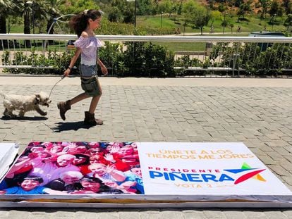 Una joven pasea en Santiago de Chile junto a un cartel electoral, el pasado domingo.