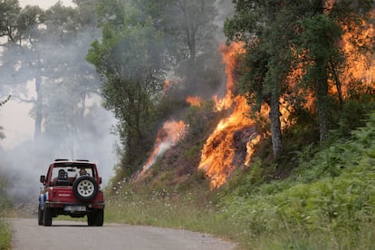 Un coche pasaba el viernes cerca de las llamas del incendio forestal de Samos (Lugo). En Galicia, una región por lo general fresca en el noroeste del país, pero que ha registrado muy altas temperaturas esta semana, varios fuegos han quemado más de 3.500 hectáreas.