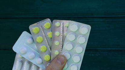hand holds pills in packs on a green background