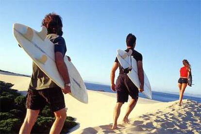 Las <b><i>webs</b></i> especializadas facilitan la búsqueda de apartamentos de alquiler para el verano, por ejemplo, cerca de las playas de Andalucía o Cataluña. En la foto, surfistas de camino a la Gran Duna, en Tarifa (Cádiz).