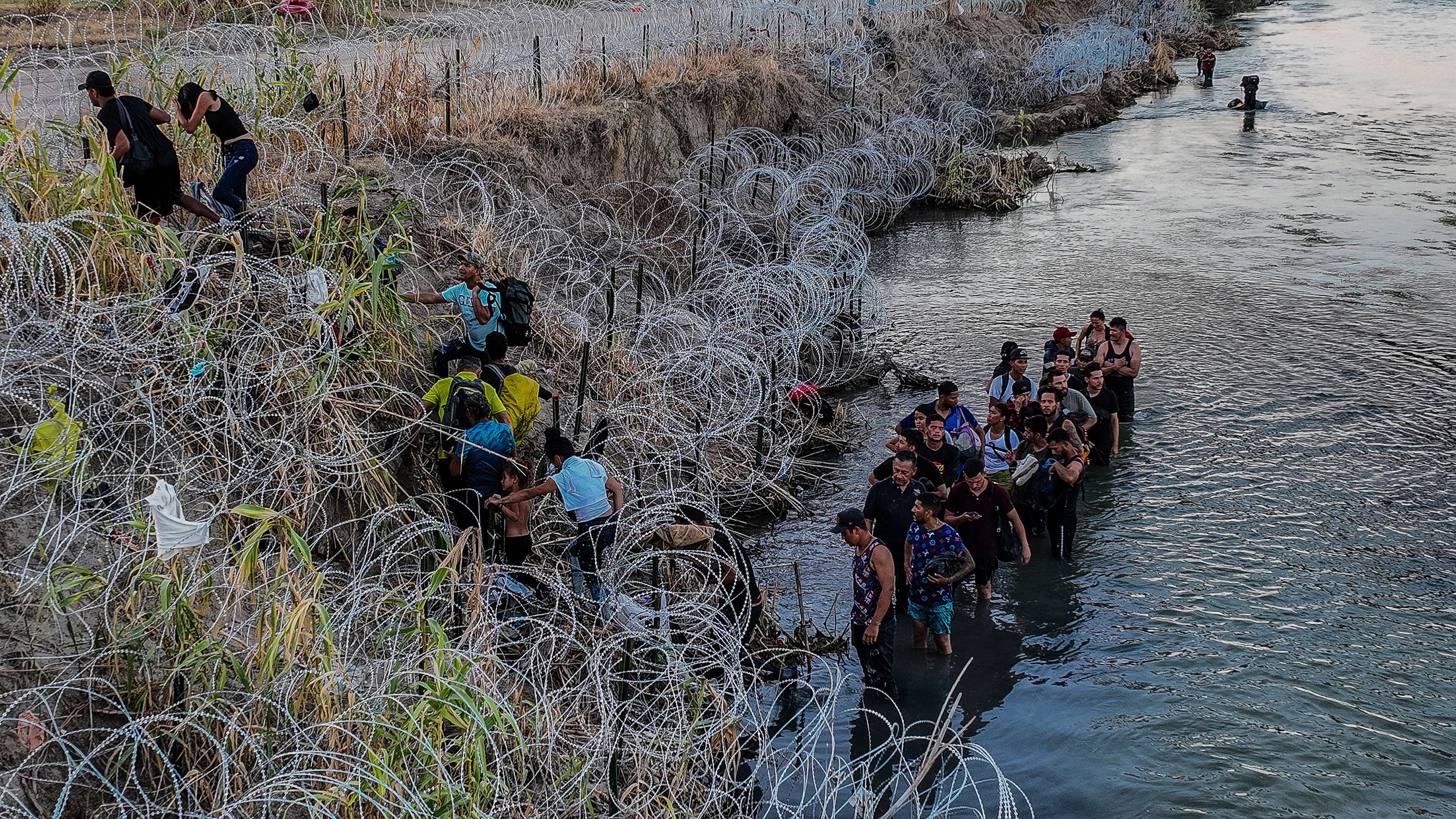 Migrantes cruzan el alambre de púas para llegar a Eagle Pass (Texas), en septiembre de 2023.