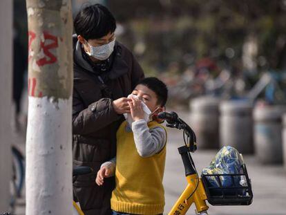 Una madre ayuda a limpiarse la cara a un niño en Wuhan. 