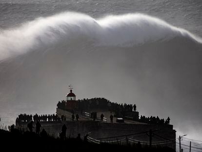 Turistas observan una ola gigante junto al fuerte de São Miguel Arcángel, en Praia do Norte, en Nazaré (Portugal).