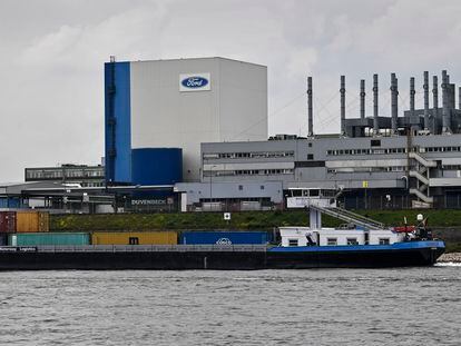 FILE - A container ship passes the Ford car plant in Cologne, Germany, May 4, 2020. Ford said that it will cut 3,800 jobs in Europe over the next three years in an effort to streamline its operations as it contends with economic headwinds and increasing competition on electric cars. The automaker said that 2,300 jobs will go in Germany. (AP Photo/Martin Meissner, File)