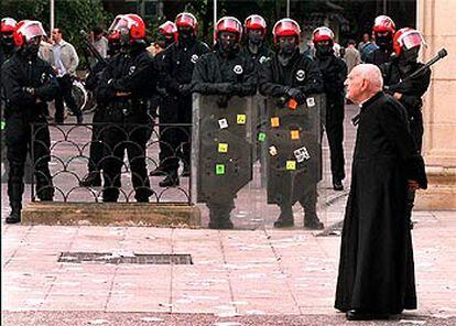 Un sacerdote paseaba ayer  frente a una patrulla de agentes de la Ertzaintza desplegados en torno a la sede del Parlamento vasco, en Vitoria.