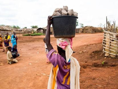 Una joven carga un cubo con pastillas de combustible en el campo de refugiados de Mbil&eacute; (Camer&uacute;n).