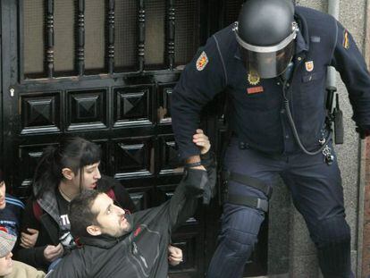 Un agente desaloja de la puerta de una vivienda de Torrej&oacute;n (Madrid), a las personas concentradas para apoyar a un desahuciado.