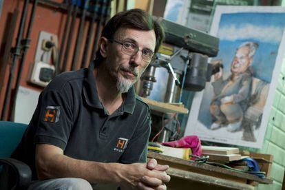 Ruben López en el taller de su padre Julio, con un retrato de éste.