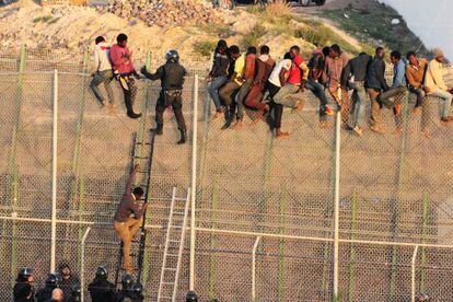Agentes de la policía bajan a un inmigrante encaramado a la valla fronteriza de Melilla en 2014.