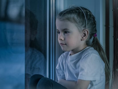 Una niña piensa apoyada en la ventana.