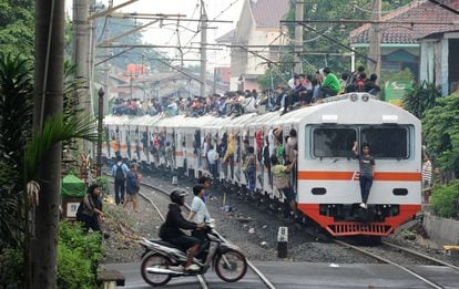 Grupos indonesios de derechos humanos han protestado contra una decisión de la compañía ferroviaria, de propiedad estatal, que pretende evitar imágenes como esta, un tren sobrecargado de pasajeros en dirección a Yakarta. La empresa ha anunciado que piensa colgar bolas de cemento sobre las vías férreas para disuadir a los <i>surferos ferroviarios</i> de que se suban a los techos de los vagones. Dicen los activistas que la decisión "pone en riesgo vidas".