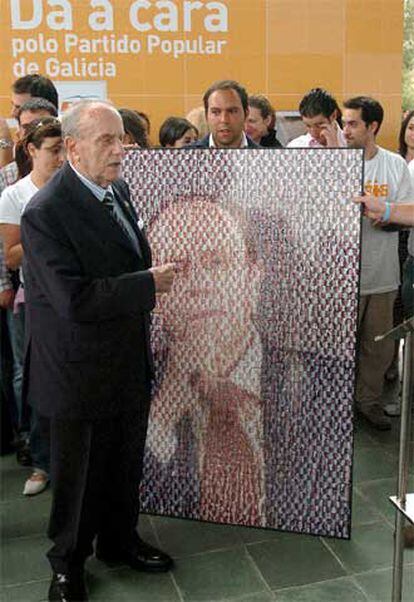 Manuel Fraga recibe un cuadro con su foto electoral realizada con pequeñas fotografía de militantes de Nuevas Generaciones ayer en Santiago.
