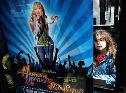 Una niña observa un cartel de la película <i>Hannah Montana / Miley Cyrus: best of both worlds Concert Tour.</i>