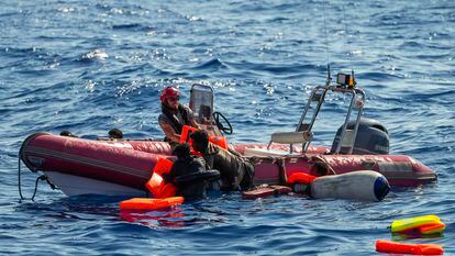 Un miembro de la tripulación del barco de Open Arms ayuda a dos migrantes a subir a una lancha de rescate tras el naufragio de la patera.