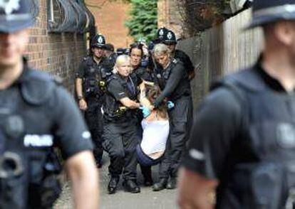 Varios policías cargan con una manifestante que participó en una protesta contra la controvertida técnica de extracción de gas conocida como fracturación hidráulica o "fracking", en la sede de la compañía energética Cuadrilla, en la localidad de Lichfield (Reino Unido).
