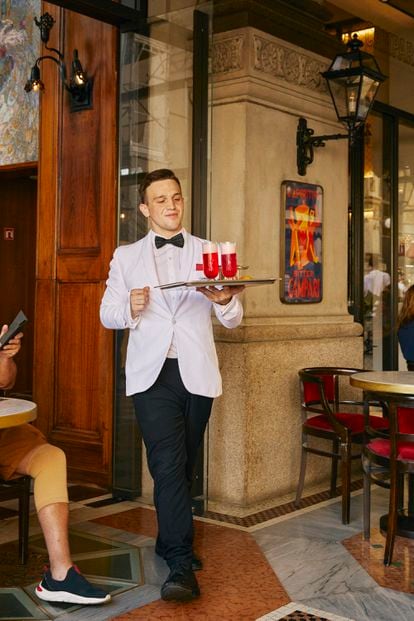 Un camarero lleva unos cócteles a la terraza de Camparino, un bar clásico del centro de Milán.