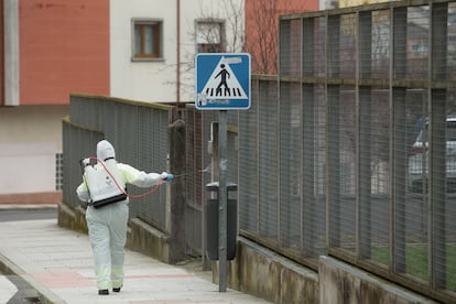 Una persona desinfecta el perímetro que rodea un colegio público gallego, en febrero de 2021 tras un brote en el centro.
