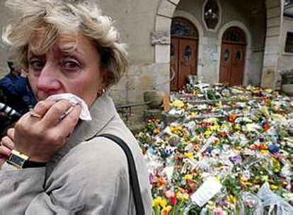 Una mujer llora ante la entrada del instituto Johannes Gutenberg, cubierta de flores por la muerte el viernes de 17 personas.