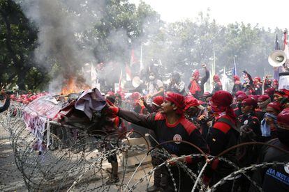 Trabajadores indonesios queman pancartas ante una alambrada montada por la policía durante una manifestación por el Día Internacional de los Trabajadores en Yakarta (Indonesia).